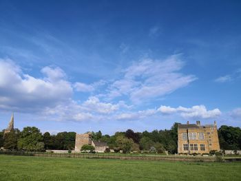 Building on field against cloudy sky