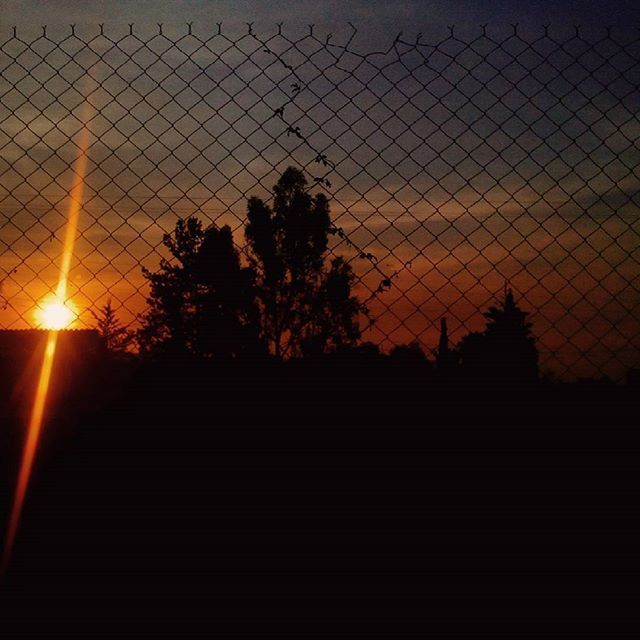 sunset, silhouette, sky, sun, orange color, tree, fence, sunlight, cloud - sky, tranquility, scenics, built structure, nature, beauty in nature, tranquil scene, railing, no people, architecture, idyllic, outdoors