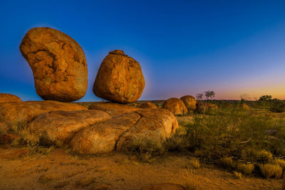 Rocks on field against blue sky