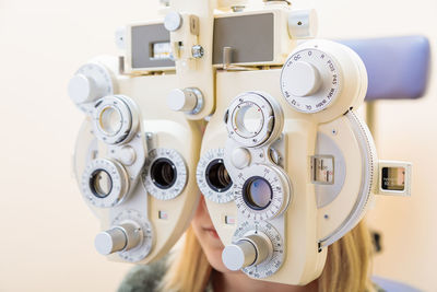 A male ophthalmologist checks a girl's eyesight using a phoropter. vision treatment