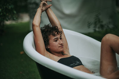 Young woman sitting in bathtub outdoors