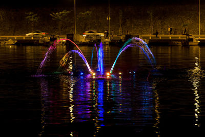 Illuminated bridge over river in city at night