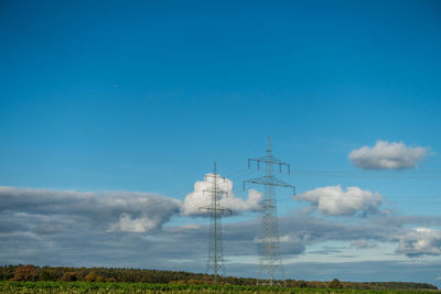 Low angle view of electricity pylon on field against sky