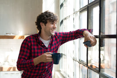 Young entrepreneur standing in company kitchen, drinking coffee