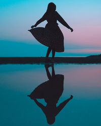 Rear view of silhouette woman standing at beach against sky