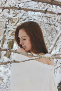 Woman wrapped in white fabric at forest during winter