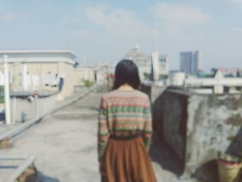 Rear view of man standing against sky in city