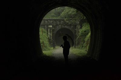 Rear view of silhouette woman standing in dark