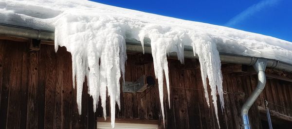 Low angle view of icicles on roof of house against sky during winter