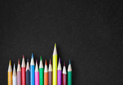 Directly above shot of multi colored pencils on table against black background