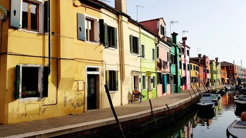 Buildings by canal against sky in city