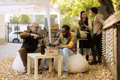 Friends using digital tablet while sitting at park