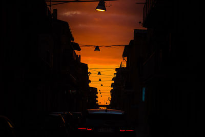 City street and buildings against sky during sunset