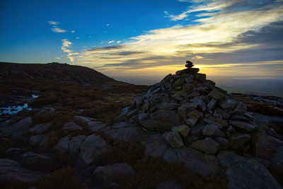 Man standing on rock against sky during sunset