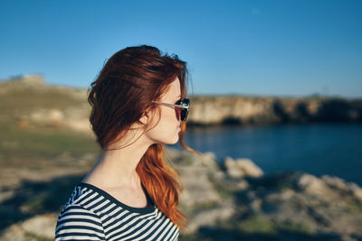 Portrait of young woman wearing sunglasses standing against sky