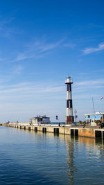 Lighthouse by building against sky