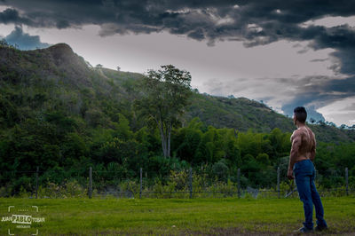 Rear view of man standing on mountain against sky