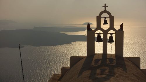 Cross by sea against sky during sunset