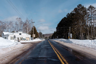 Road by trees against sky during winter