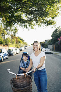 Portrait of happy mother and son with bicycle on street