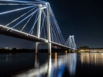 Illuminated bridge over river against sky at night