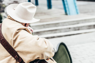 Close-up of person wearing hat sitting outdoors