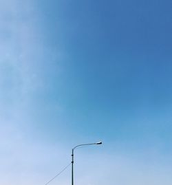 Low angle view of telephone pole against clear blue sky