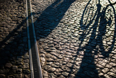 Shadow of bicycle on footpath during sunny day