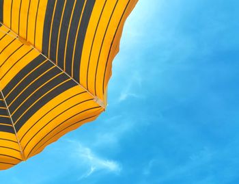 Low angle view of yellow beach umbrella against sky