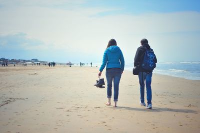 Rear view of people walking on beach