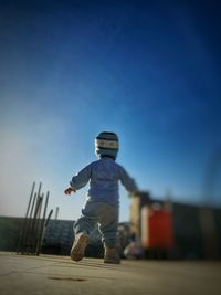 Rear view of boy jumping against sky