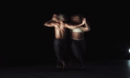 Midsection of shirtless man standing against black background