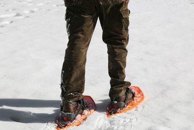 Young man on white snow with orange snowshoes