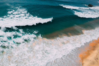 High angle view of waves rushing towards shore at beach