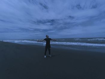 Rear view of man standing on beach against sky