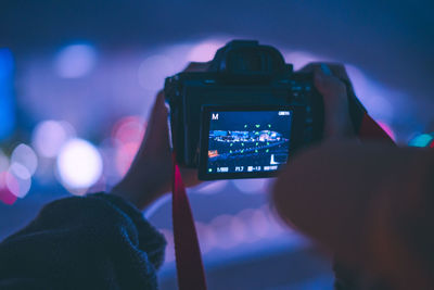 Cropped hand photographing with camera at night