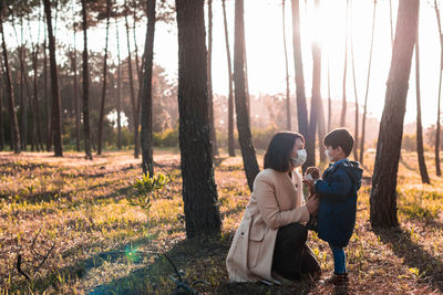 Side view of mother and son wearing masks in forest