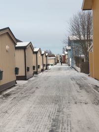 Empty road amidst buildings against sky during winter