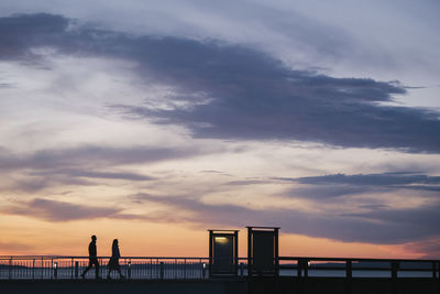 Silhouette people by sea against sky during sunset