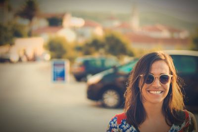 Smiling young woman wearing sunglasses on street