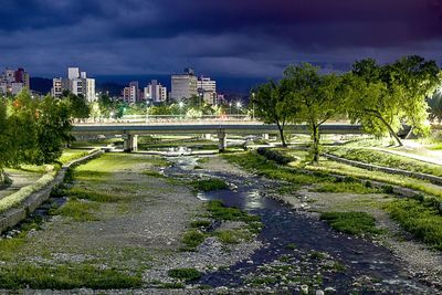 Bridge over river by buildings in city against sky