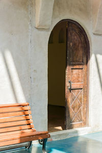 Empty bench by door outdoors