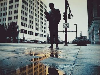 Rear view of man standing on road in rain