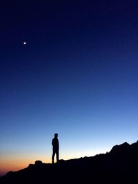 Low angle view of silhouette man standing against blue sky