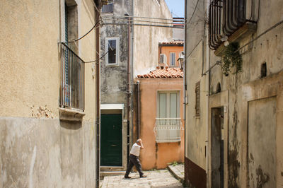 Rear view of woman walking on street amidst buildings