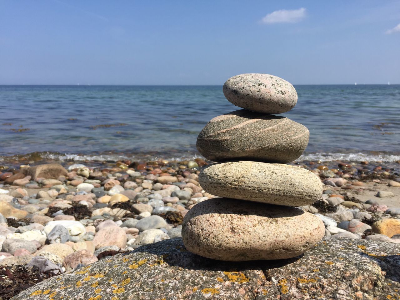 sea, stack, rock - object, pebble, water, stone - object, tranquility, balance, tranquil scene, horizon over water, scenics, stone, nature, sky, beauty in nature, shore, blue, rock, large group of objects, idyllic, outdoors, day, no people, abundance, non-urban scene, focus on foreground, close-up