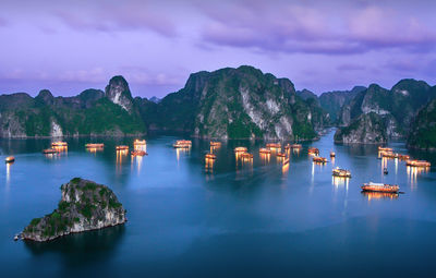 Aerial view of illuminated boats on sea against cloudy sky