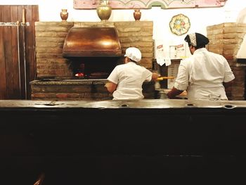 Rear view of people working in kitchen