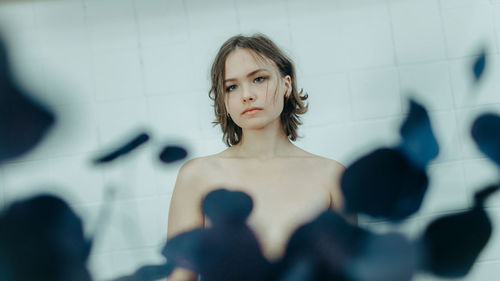 Portrait of young woman standing against wall