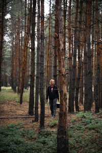 Man standing amidst trees in forest